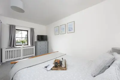 a white bedroom with a bed and a window at The Old Hay Barn, Hot Tub, Pet Friendly in Ludgvan