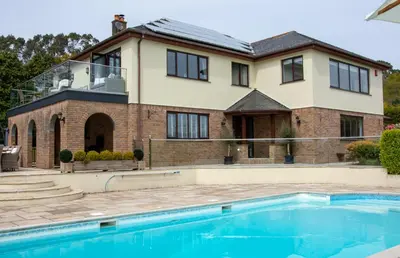 a house with a swimming pool in front of a house at Hewas Water House - Private Pool, Hot Tub & Games Room in Grampound
