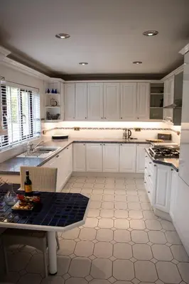 a kitchen with white cabinets and a table in it at Hewas Water House - Private Pool, Hot Tub & Games Room in Grampound