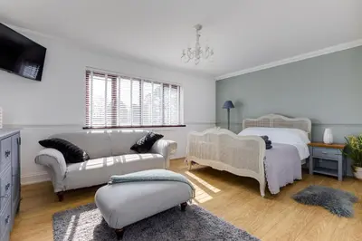 a bedroom with two beds and a couch and a tv at Hewas Water House - Private Pool, Hot Tub & Games Room in Grampound