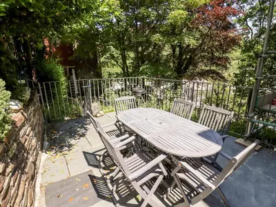 a wooden table and chairs with a fence at Lewarne in Boscastle