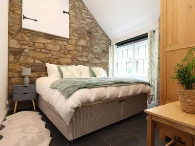 a bed in a room with a stone wall at The Dairy in Helston