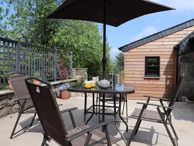 a table and chairs with an umbrella on a patio at The Dairy in Helston