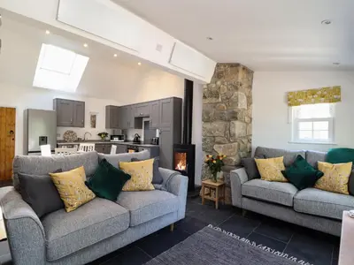 a living room with two couches and a kitchen at The Dairy in Helston