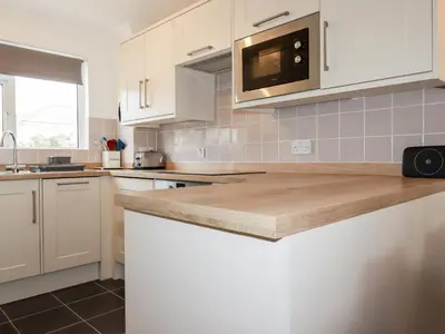a kitchen with white cabinets and a counter top at 7 Europa Court in Newquay
