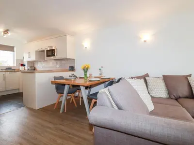 a living room and kitchen with a couch and a table at 7 Europa Court in Newquay