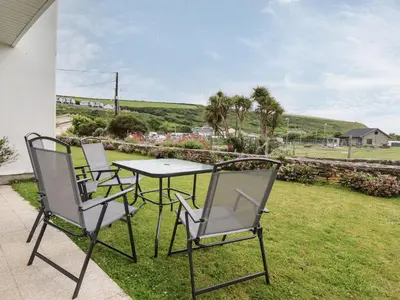 three chairs and a table on a patio at 7 Europa Court in Newquay
