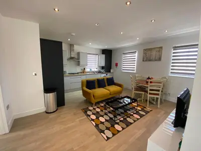 a living room with a yellow couch and a table at Apartment No 8 - Stay in style in the heart of the Cathedral City. in Truro