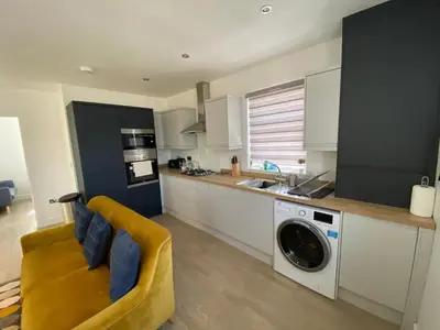 a kitchen with a washing machine and a yellow couch at Apartment No 8 - Stay in style in the heart of the Cathedral City. in Truro