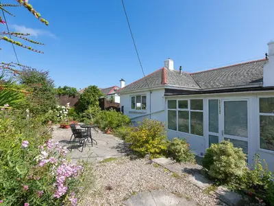 a blue house with a table and chairs in a garden at Brynmaur in St Ives