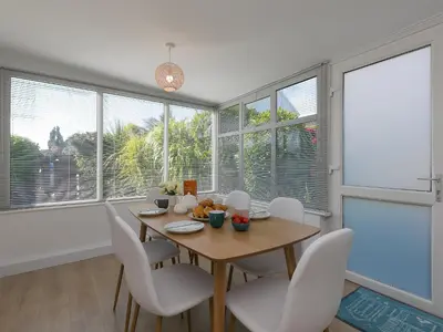 a dining room with a table and chairs and windows at Brynmaur in St Ives