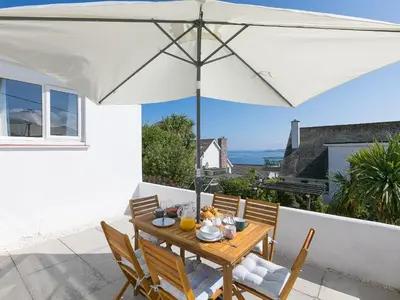 a wooden table with an umbrella on a patio at Brynmaur in St Ives