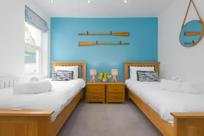 two beds in a room with a blue wall at Summer Salt in St Ives