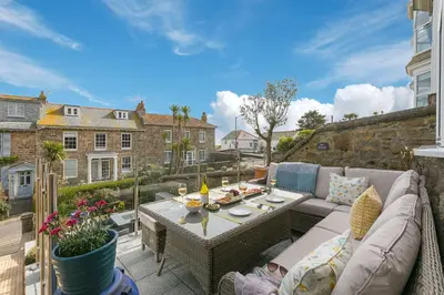 a patio with a couch and a table on a balcony at Summer Salt in St Ives
