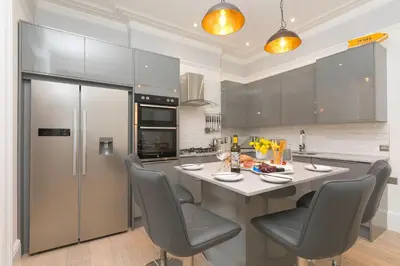 a kitchen with a table with chairs and a refrigerator at Summer Salt in St Ives