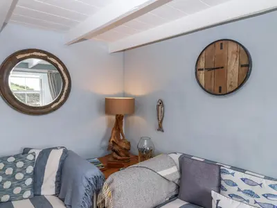 a living room with a couch and a mirror at 2 Cliff Cottages in Truro