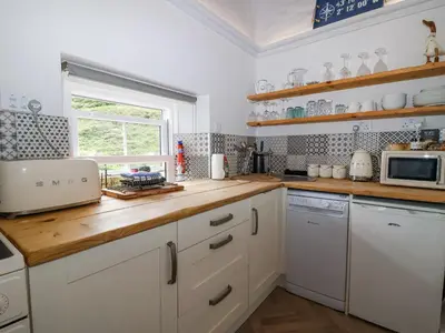 a kitchen with white cabinets and a wooden counter top at 2 Cliff Cottages in Truro