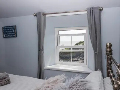 a bedroom with a bed and a window at 2 Cliff Cottages in Truro