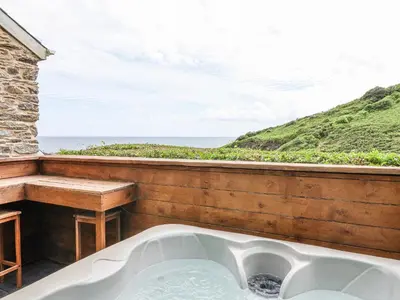 a bath tub on a balcony with a view of the ocean at 2 Cliff Cottages in Truro