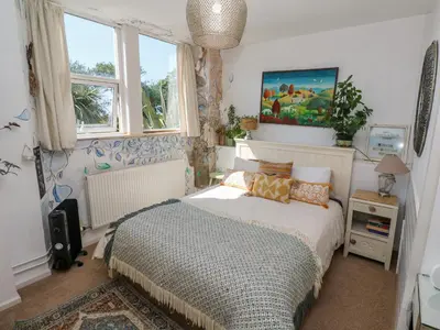 a bedroom with a bed in a room with windows at The Cottage in Penzance