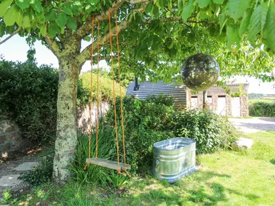 a metal ball hanging from a tree with a bucket at The Cottage in Penzance