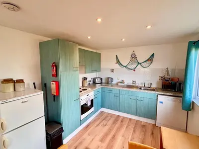 a kitchen with blue cabinets and white appliances at Trevone - Chalet 130 in Padstow