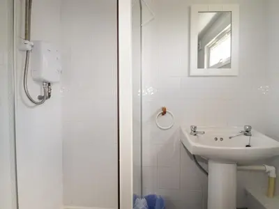 a white bathroom with a sink and a shower at Trevone - Chalet 130 in Padstow