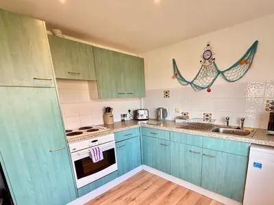 a kitchen with blue cabinets and a stove and a sink at Trevone - Chalet 130 in Padstow