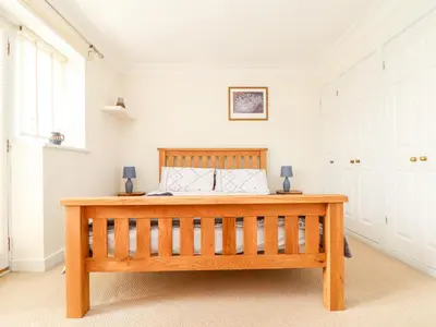 a bedroom with a wooden bed with white walls at The Wesley Apartment in Falmouth