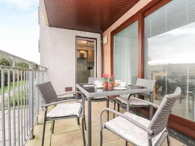 a patio with a table and chairs on a balcony at The Wesley Apartment in Falmouth