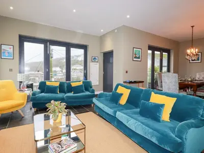 a living room with blue couches and yellow pillows at Postcard Lodge in Fowey