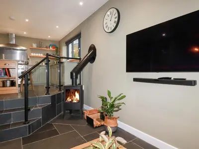 a living room with a fireplace and a clock at Postcard Lodge in Fowey