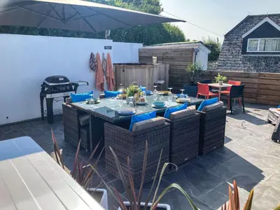 a patio with a table and chairs and a grill at Postcard Lodge in Fowey