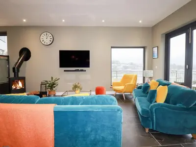 a living room with two blue couches and a clock at Postcard Lodge in Fowey
