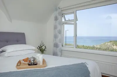 a bedroom with a bed with a tray of food and a window at Little Close - Sea Views - Parking For 3 Cars - BBQ Area in Newquay