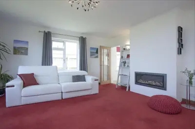 a living room with a white couch and a fireplace at Little Close - Sea Views - Parking For 3 Cars - BBQ Area in Newquay