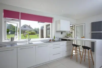a kitchen with white cabinets and a large window at Little Close - Sea Views - Parking For 3 Cars - BBQ Area in Newquay