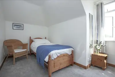 a bedroom with a bed and a chair and a window at Little Close - Sea Views - Parking For 3 Cars - BBQ Area in Newquay