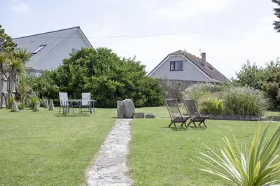 a garden with chairs and a table in the grass at Little Close - Sea Views - Parking For 3 Cars - BBQ Area in Newquay
