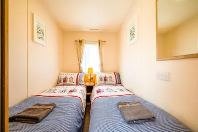 two beds in a small room with a window at The Seascape, Padstow in Padstow