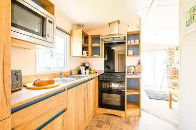 a kitchen with wooden cabinets and a stove top oven at The Seascape, Padstow in Padstow