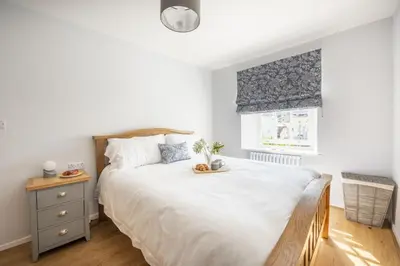 a bedroom with a large white bed and a window at The Hideaway in Porthleven