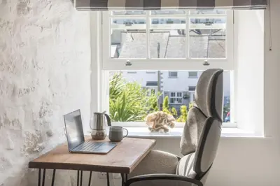 a laptop on a wooden table in front of a window at The Hideaway in Porthleven