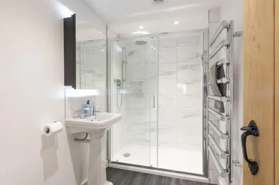 a white bathroom with a shower and a sink at The Hideaway in Porthleven