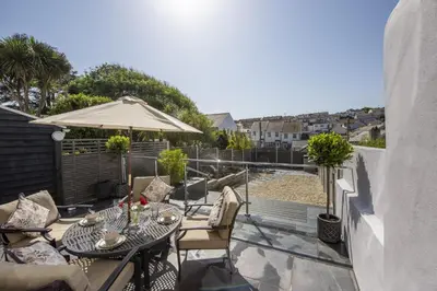 a balcony with a table and chairs and an umbrella at The Hideaway in Porthleven
