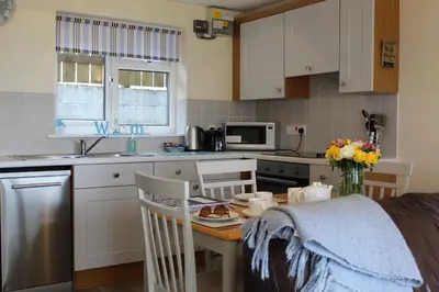 a kitchen with a table and a kitchen with a table and chairs at Lobster Pot - Mount Brioni in Downderry