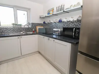 a kitchen with white cabinets and a microwave at Rock Pool House in Helston