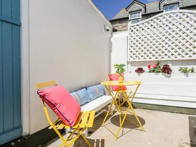 a patio with two chairs and a table and a bench at Rock Pool House in Helston