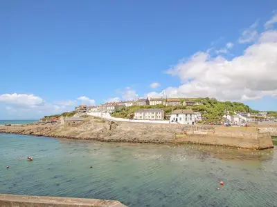 a group of houses on a hill next to the water at Rock Pool House in Helston