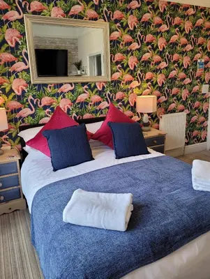 a bedroom with a large bed with a floral wall at Lansdowne Simply Stay in Redruth